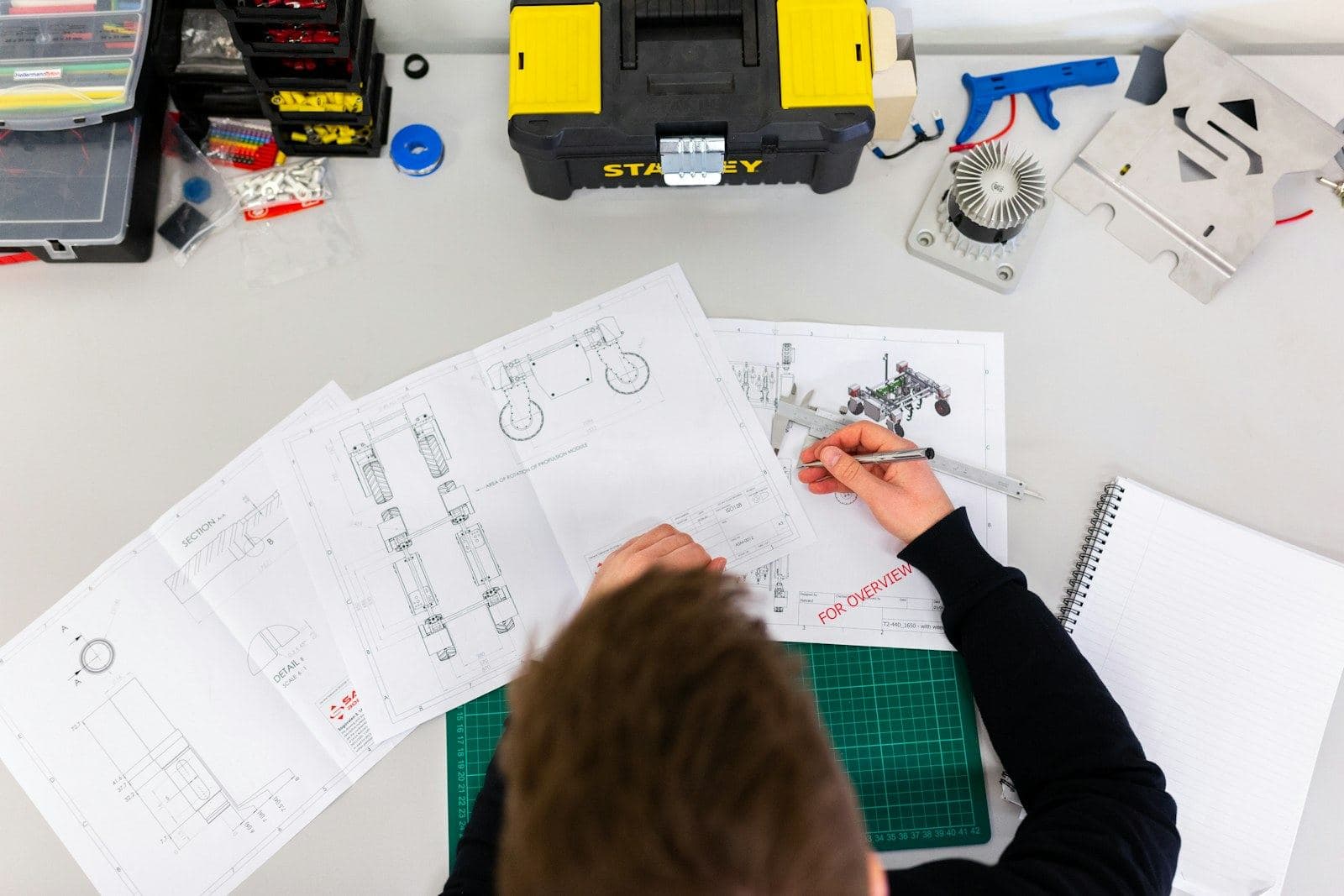 An engineer marking up technical drawings on a desk