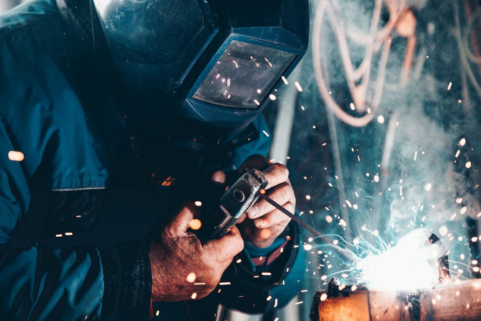A welder in a mask working on a steel part